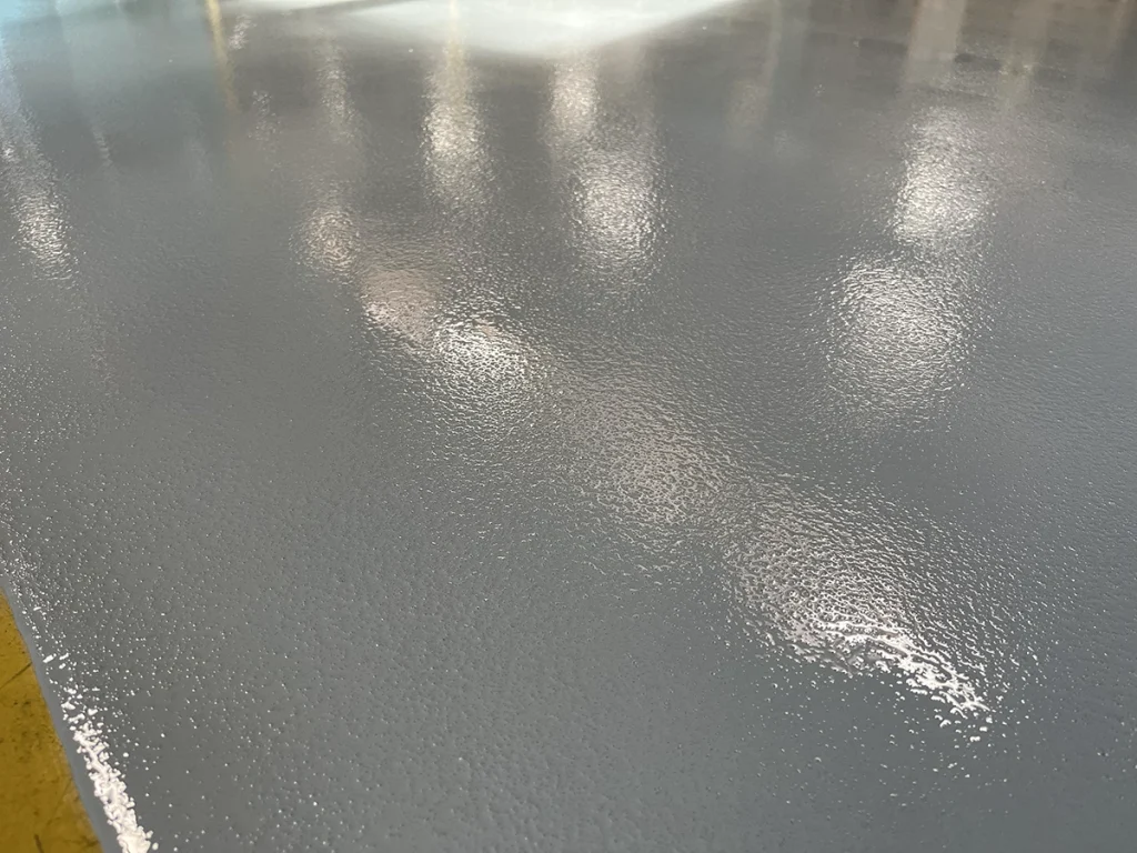 Zoom sur une résine de sol industrielle antidérapante de couleur grise montrant la texture avec grain et la finition
